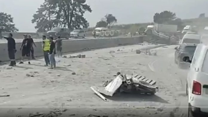 Camión de carga volcado sobre la autopista México-Puebla con material y escombros esparcidos por la cinta asfáltica tras un choque múltiple.