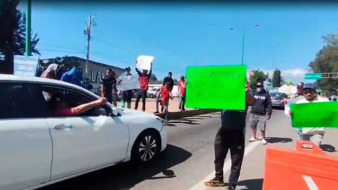 Cortadores de aguacate solicitando apoyo económico a los automovilistas en el Boulevard Industrial de Uruapan.