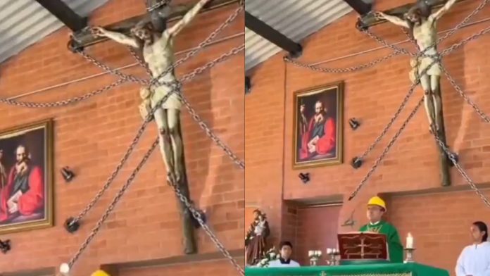 Un Cristo de madera asegurado con gruesas cadenas para evitar accidentes en la iglesia.