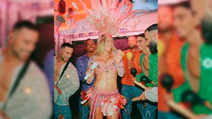 La cantante colombiana Karol G luciendo un llamativo penacho de plumas rosas durante una de sus recientes presentaciones musicales.