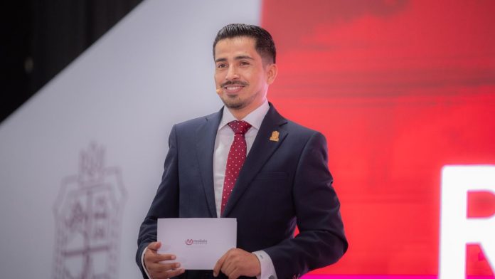 moisés Navarro Arellano, coordinador de alcaldes de Morena, hablando frente a un micrófono durante asamblea en Michoacán.